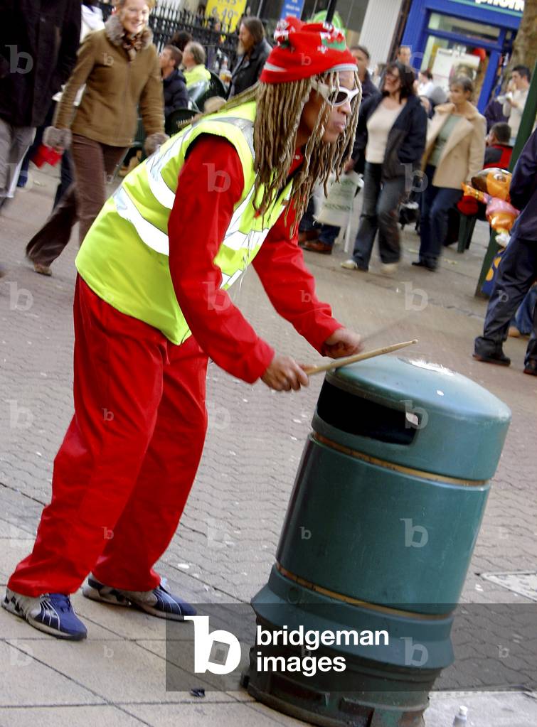 Busker in dreadlocks drumming