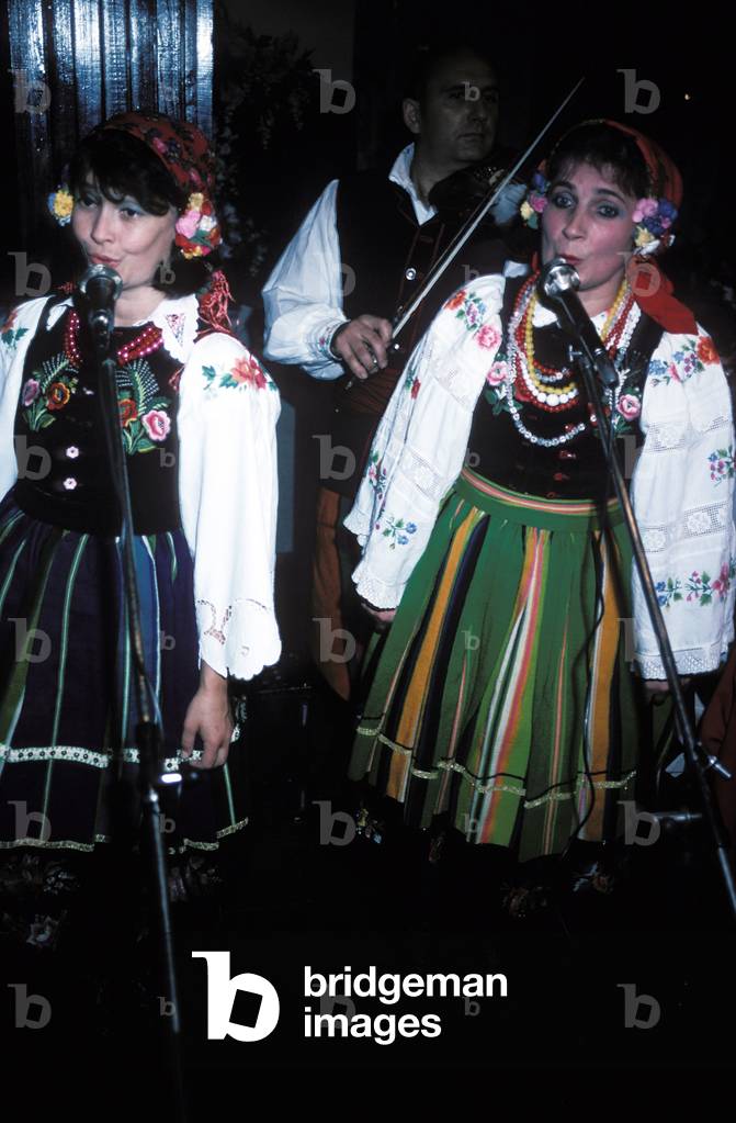 Polish folk singers performing concert in traditional folk dress, with violinist