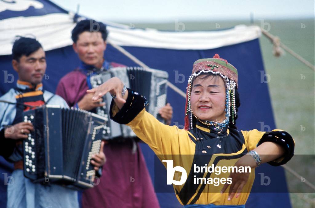 Mongolian dancer performing folk dance in traditional dress, with accordion players, Gobi