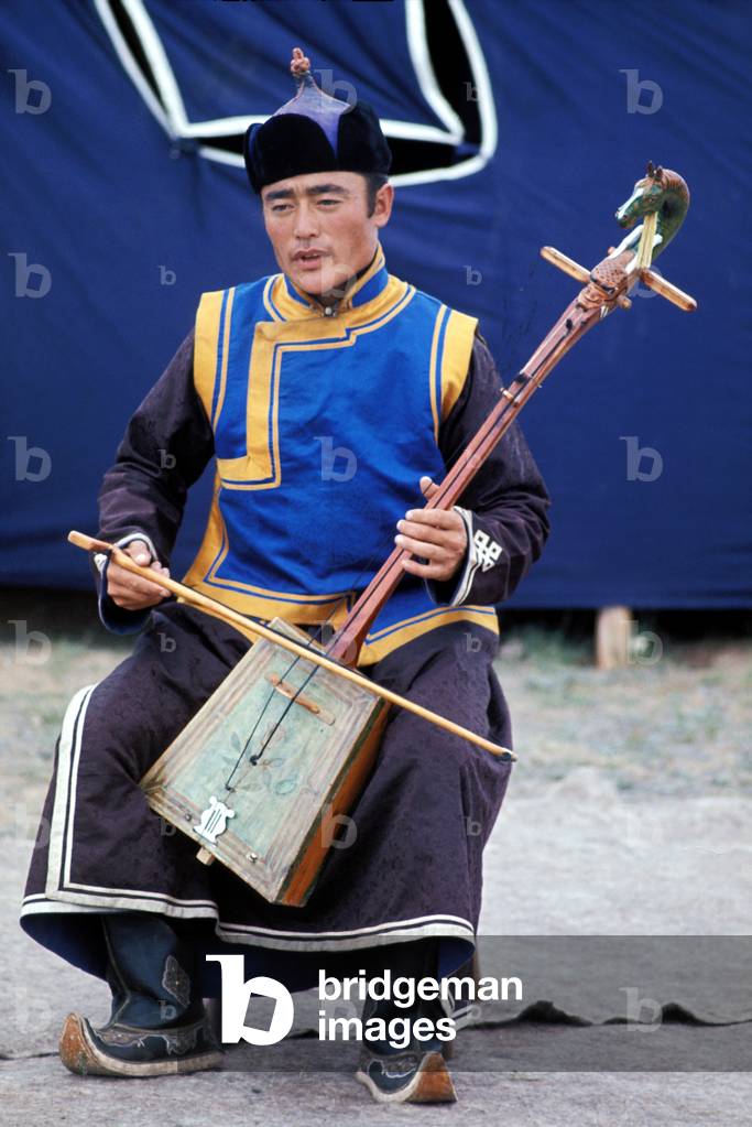 Mongolian musician playing traditional instrument, in folk dress, Gobi