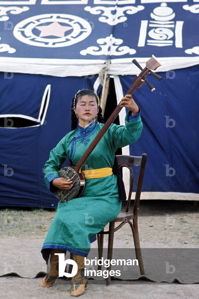 Mongolian musician playing traditional instrument, in folk dress, Gobi
