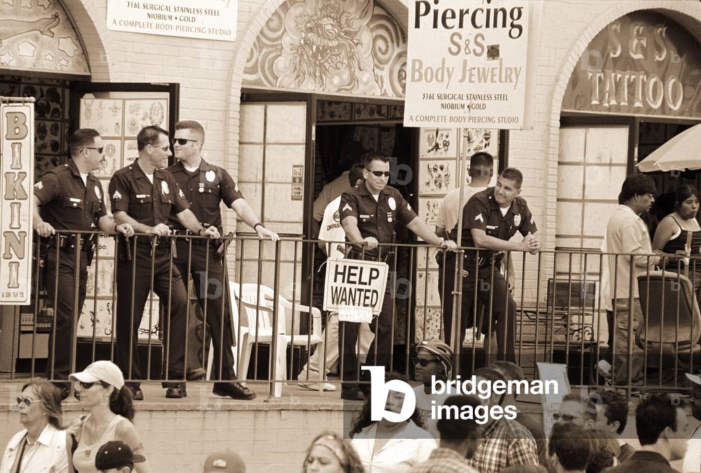 Police gathered behind a 'Help Wanted' sign, 2004 (photography)