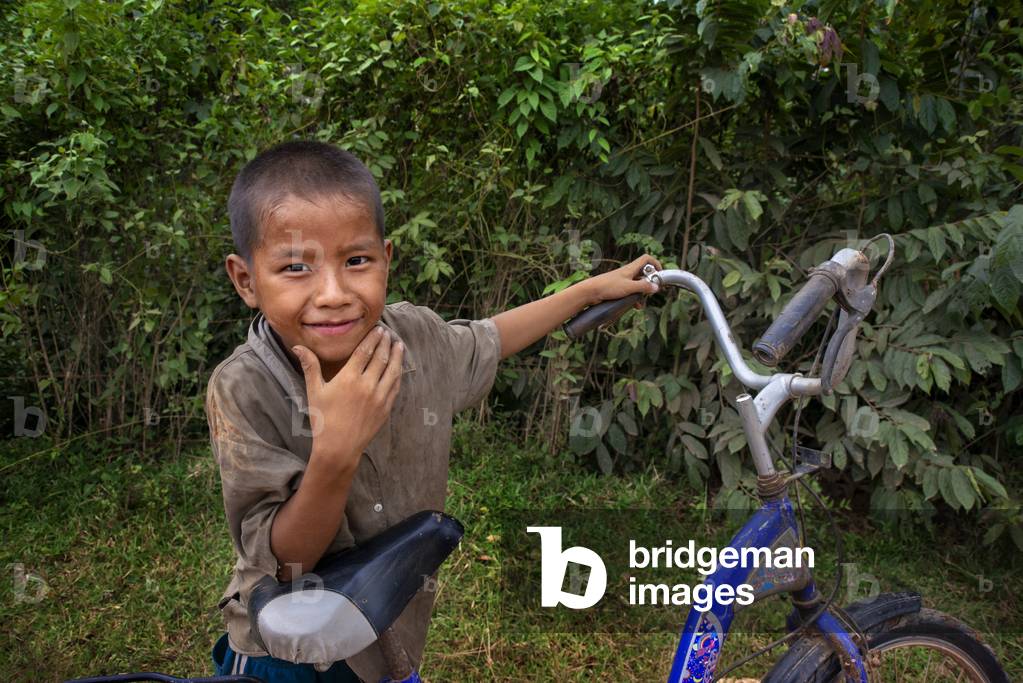 Young local boy with a bicycle in Vang Vieng village, Laos (photo)