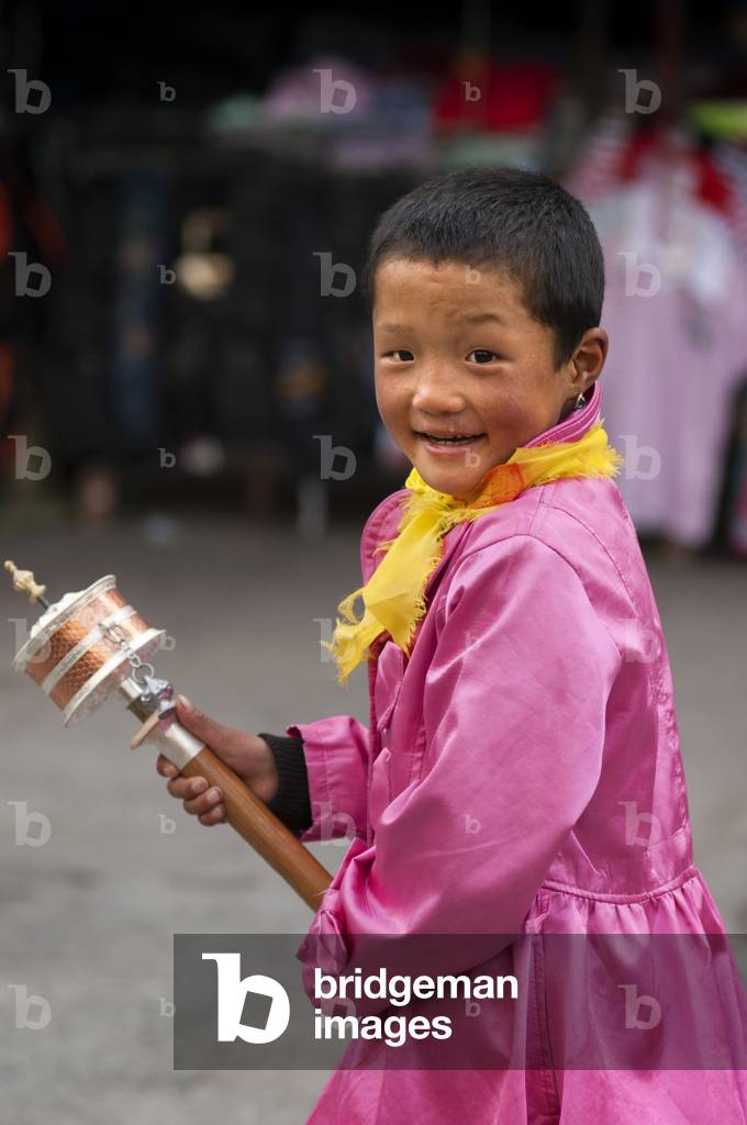 A Tibetan child spinning his prayer mill in the streets of Lhasa near Jokhang temple, Lhasa Tibet (photo)