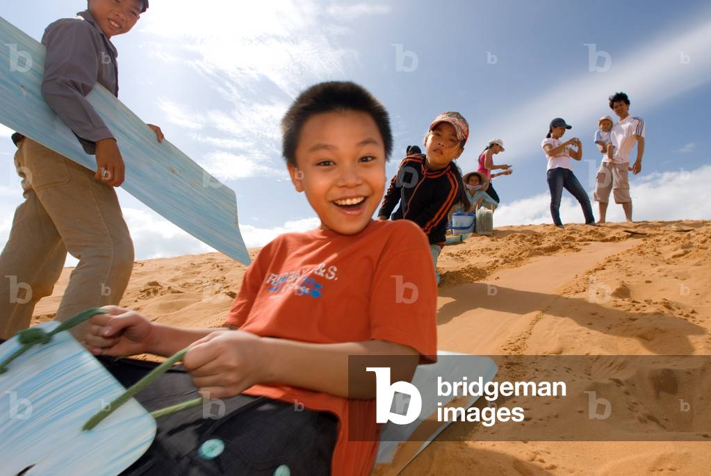 Young people have fun throwing themselves through the desert sand at the White Sand Dunes, Mui Ne, Vietnam (photo)