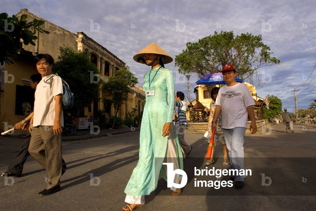A guide along with several tourists through the old city of Hoi An, Vietnam (photo)
