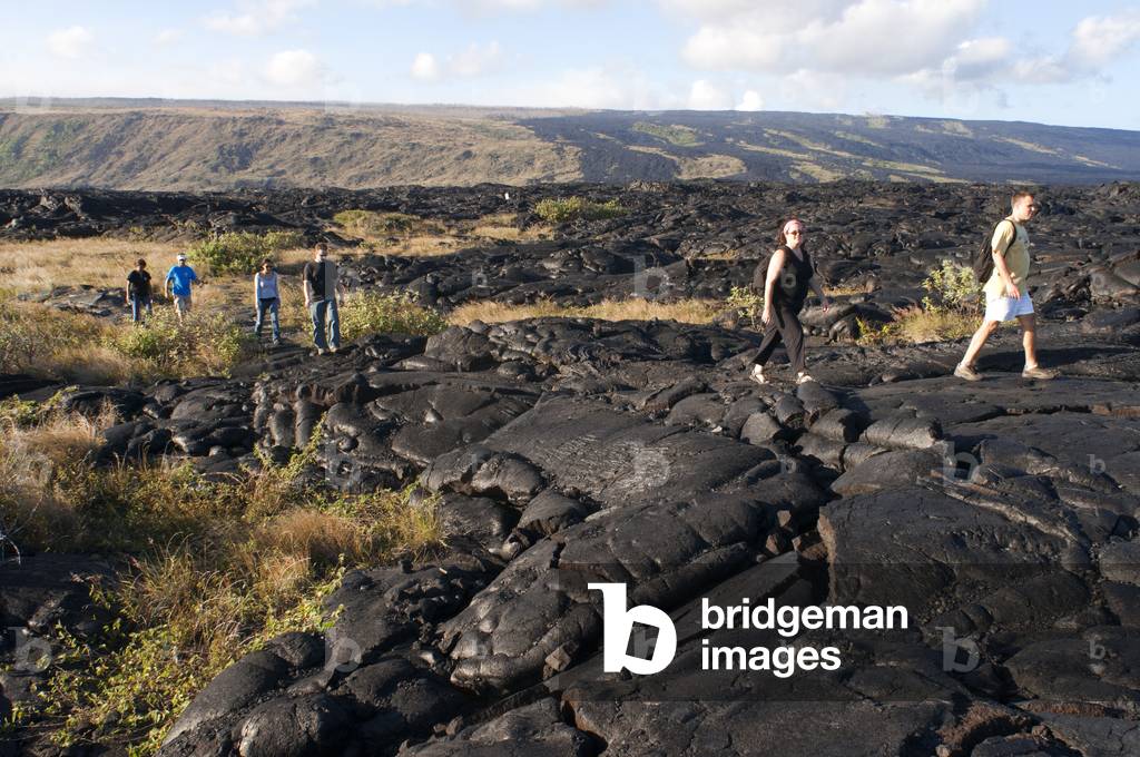 Tourists walking over the black lava mountains near Chain of Craters Road, Hawaii Volcanoes National Park, Big Island, Hawaii (photo)