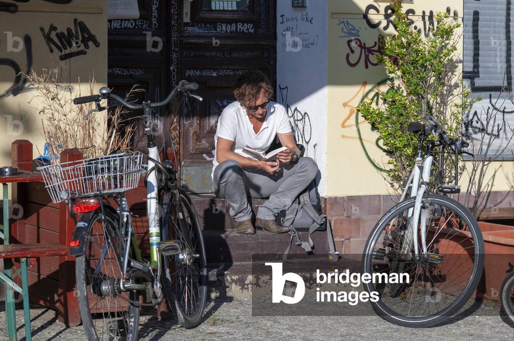 Man reading a book in a old house in Prenzlauer Berg district in Berlin, Germany (photo)
