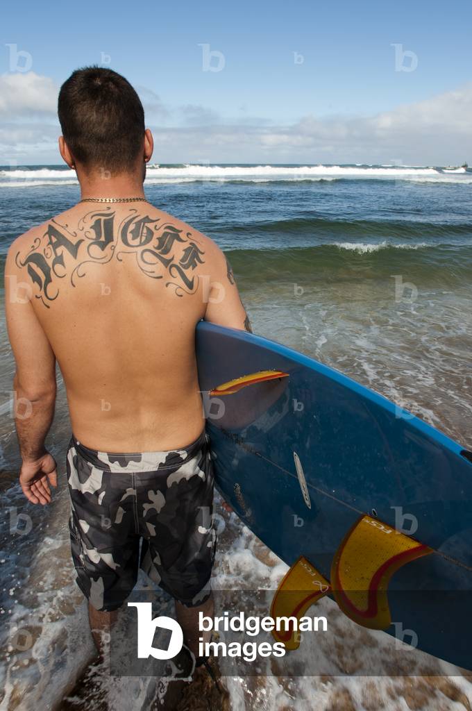 Surfer on the beach at Ali'i Beach Park, Haleiwa, O'ahu, Hawaii (photo)