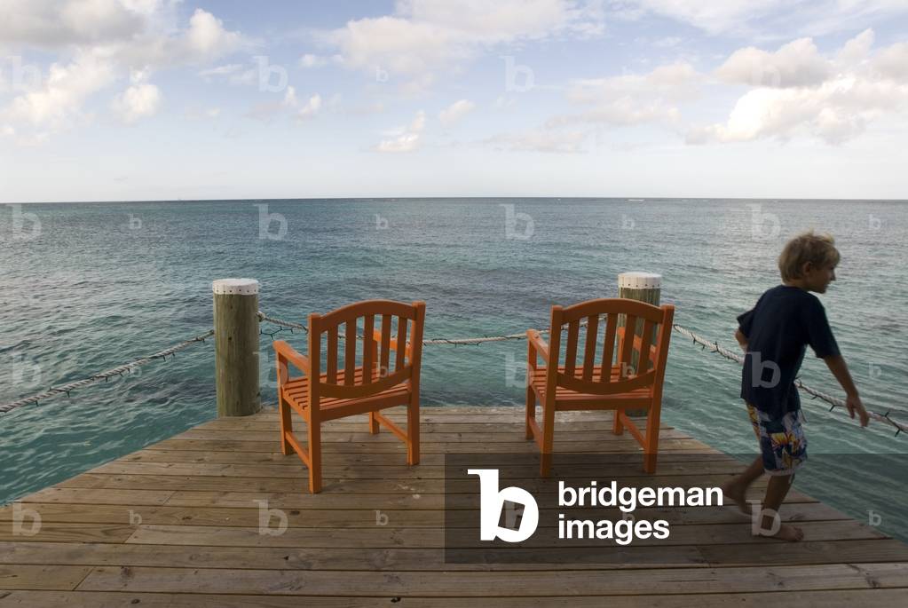 Child at wooden pier at Hotel Compass Point Resort at Love beach Nassau, Bahamas, Caribbean (photo)