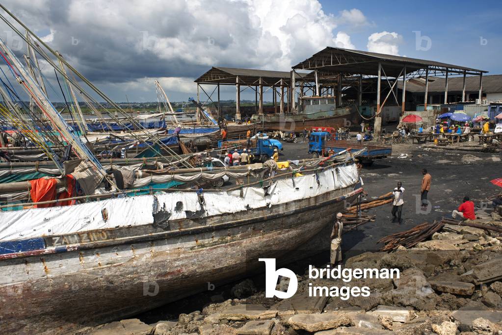 Hard workers working in the harbur of Stone Town, unloading traditional dhow in Zanzibar, Tanzania, Africa (photo)