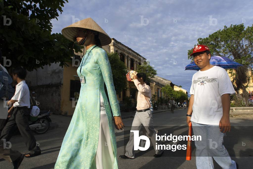 A guide along with several tourists through the old city of Hoi An, Vietnam (photo)