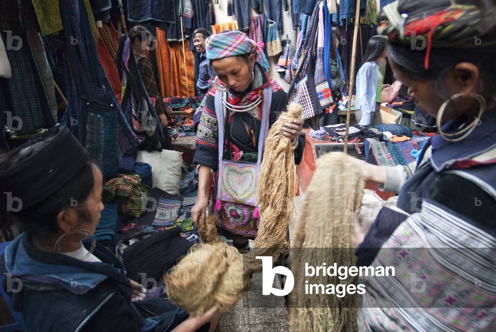 Black hmong women making and selling tribal handicrafts and clothes iniside the market in Sapa, Lao Cai Province, Vietnam (photo)