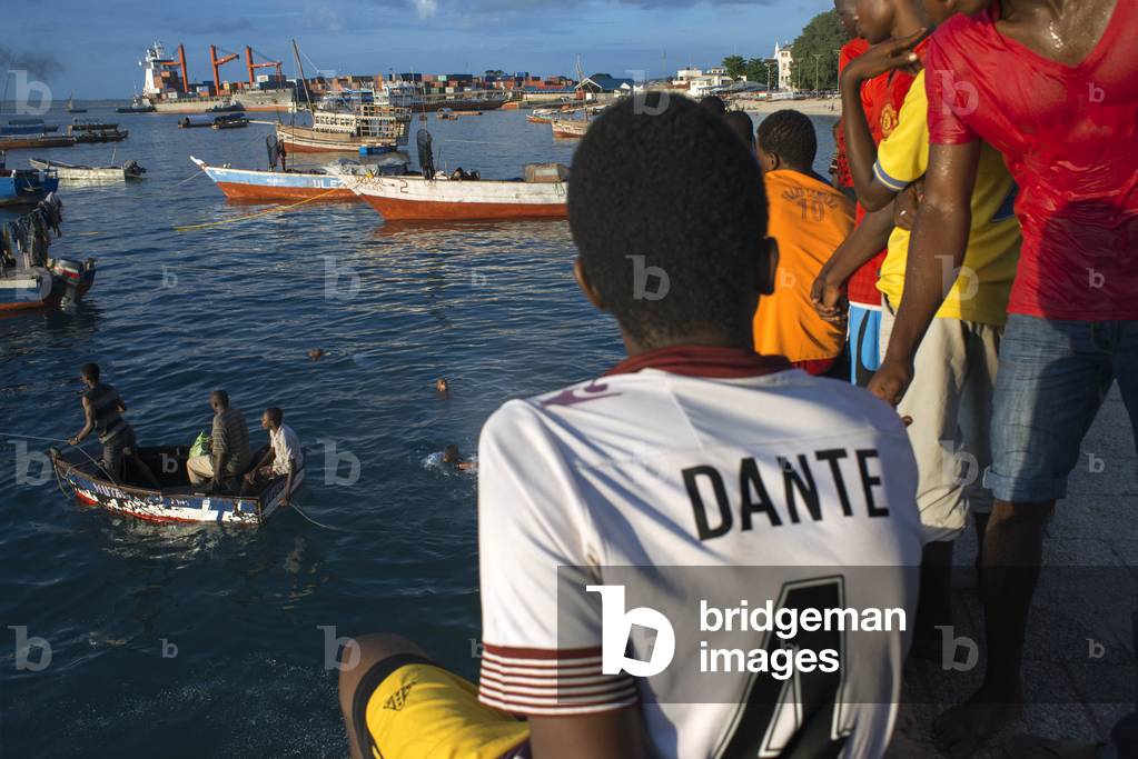 Local boys looking the fishermen in the Malecon next to the pier in Stone Town, Zanzibar, Tanzania, Africa (photo)