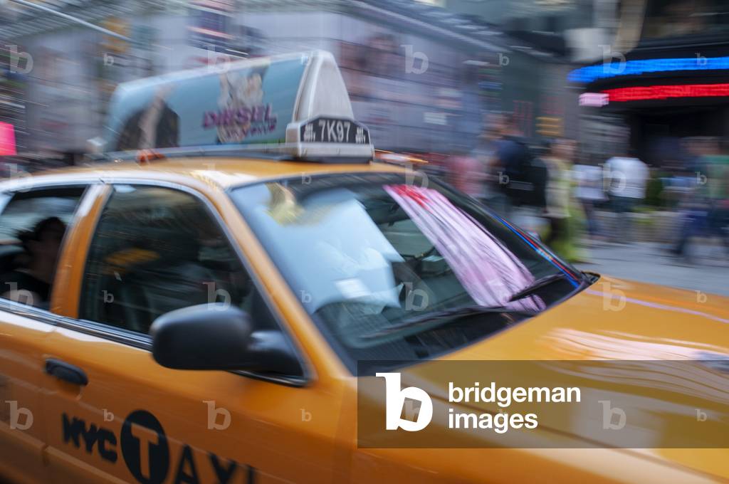 Yellow New York taxi cab driving fast on a street in New York City, USA (photo)