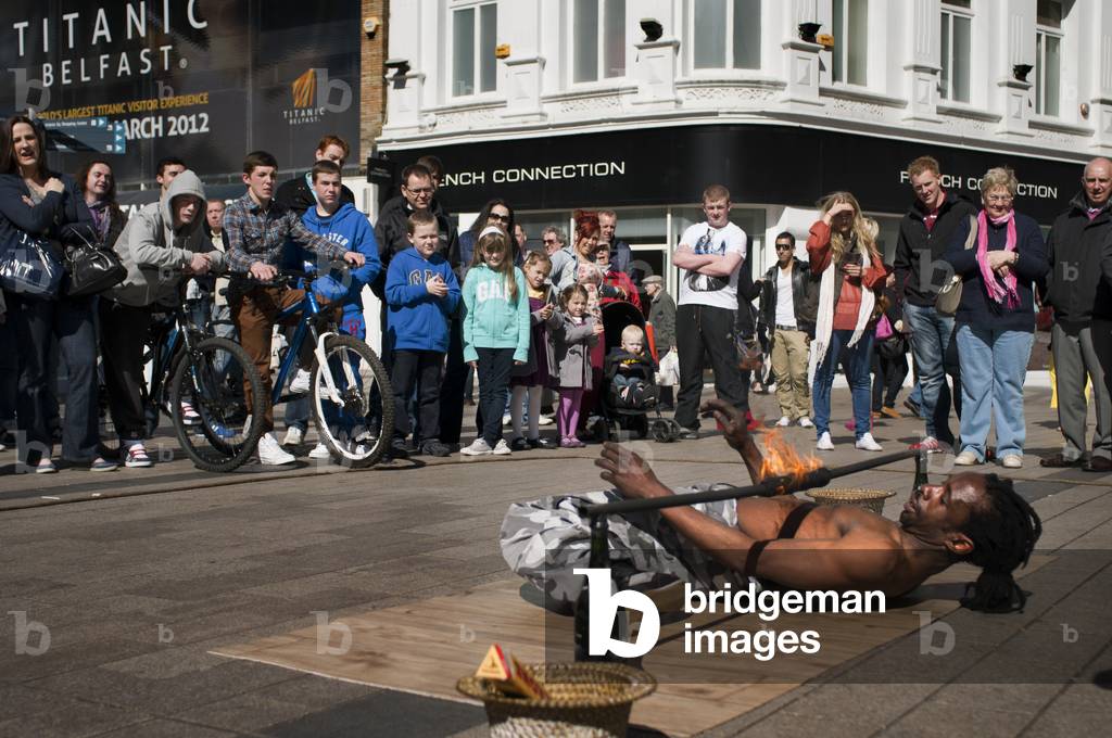 A juggler tries to pass under the fire in Arthur Square, Belfast, Northern Ireland, UK (photo)