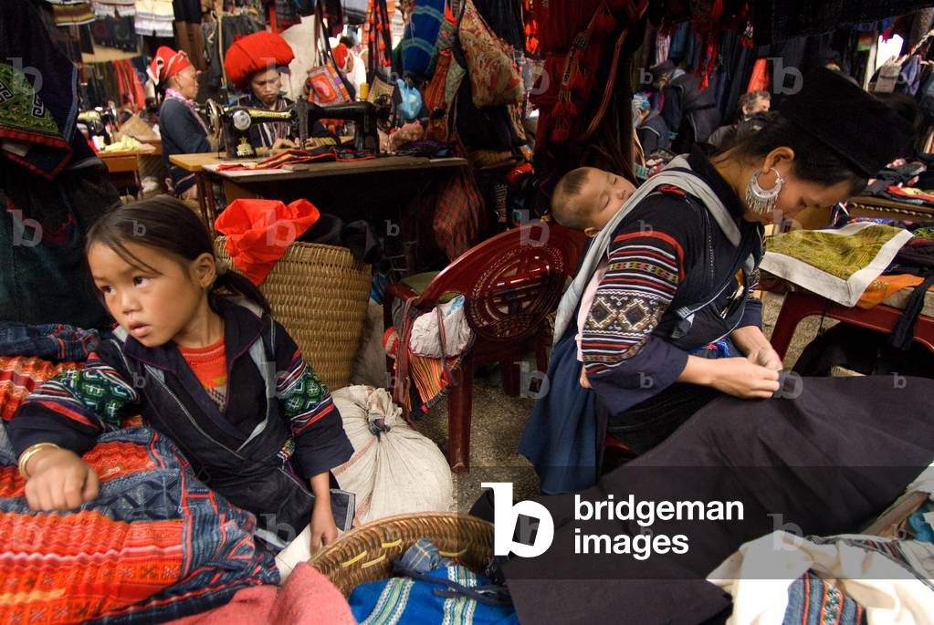 Black hmong women making and selling tribal handicrafts and clothes iniside the market in Sapa, Lao Cai Province, Vietnam (photo)