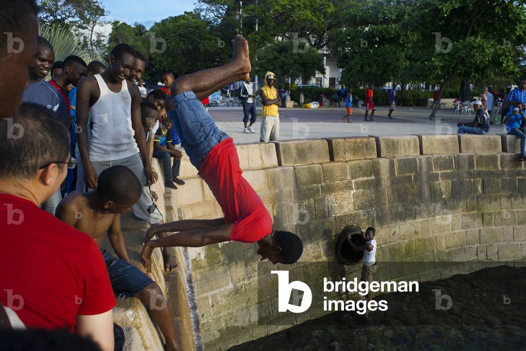 Local boys jumping off the Malecon into the sea next to the pier in Stone Town, Zanzibar, Tanzania, Africa (photo)