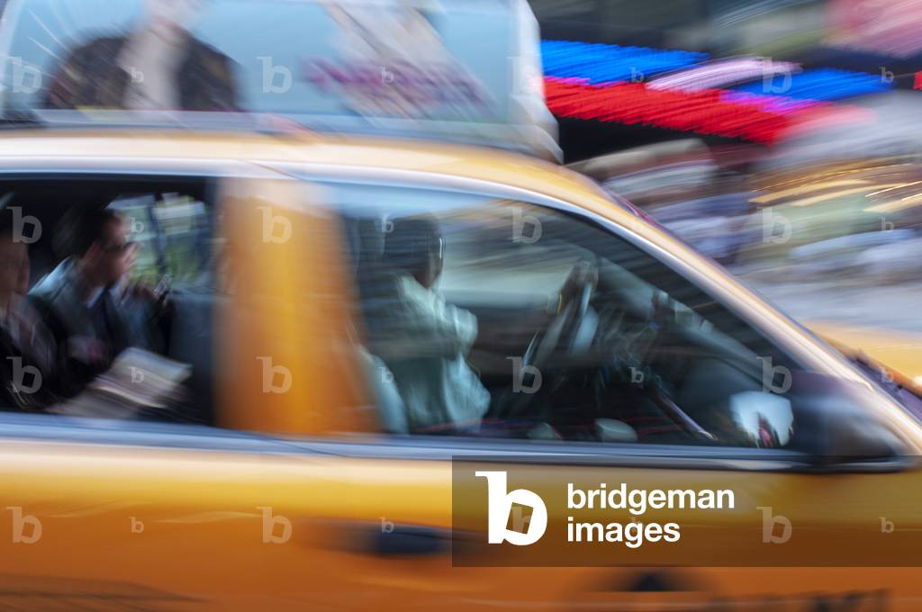 Yellow New York taxi cab driving fast on a street in New York City, USA (photo)