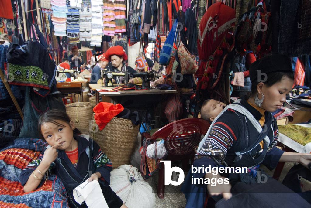 Black hmong women making and selling tribal handicrafts and clothes iniside the market in Sapa, Lao Cai Province, Vietnam (photo)