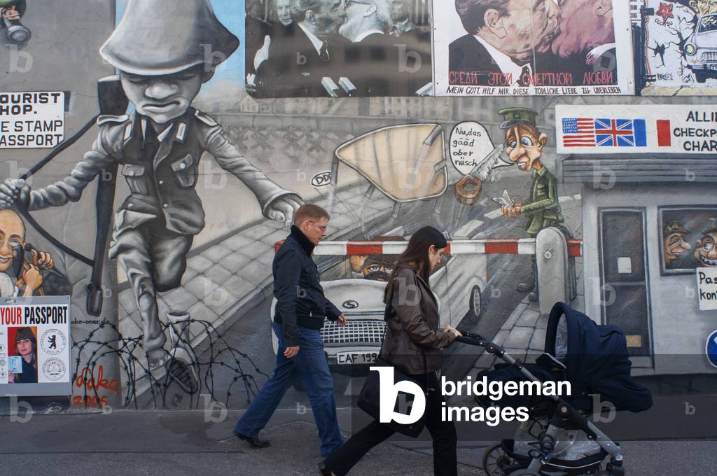Graffiti on original section of Berlin Wall at the East Side Gallery in Friedrichshain with graffiti representing Checkpoint Charlie Berlin, Germany (photo)