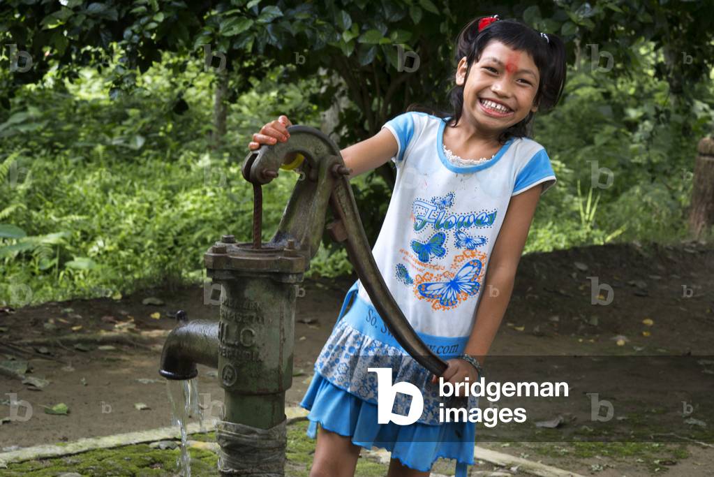 A girl having fun drawing water from a well, Bharatpur, Ratnanagar, Chitwan National Park, Nepal, Asia (photo)
