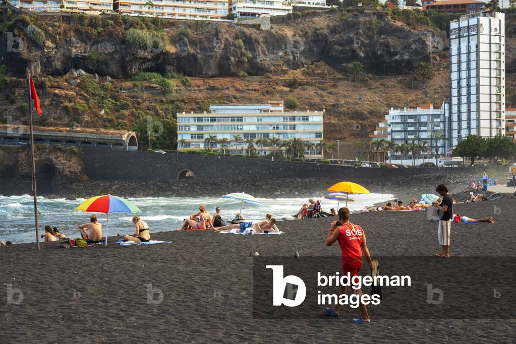 Tourists at los gigantes cliffs volcanic black sand beach in Puerto de la Cruz, Tenerife Island, Canary Islands, Spain (photo)