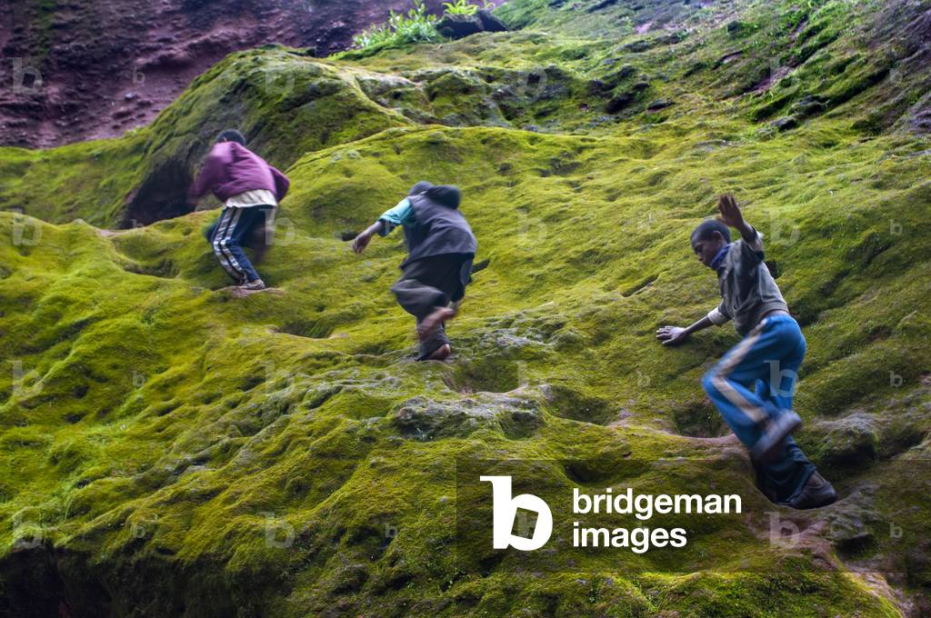 Local children running and the traditional house with thatched roof and farmland in the mountain, Lalibela, Ethiopia (photo)