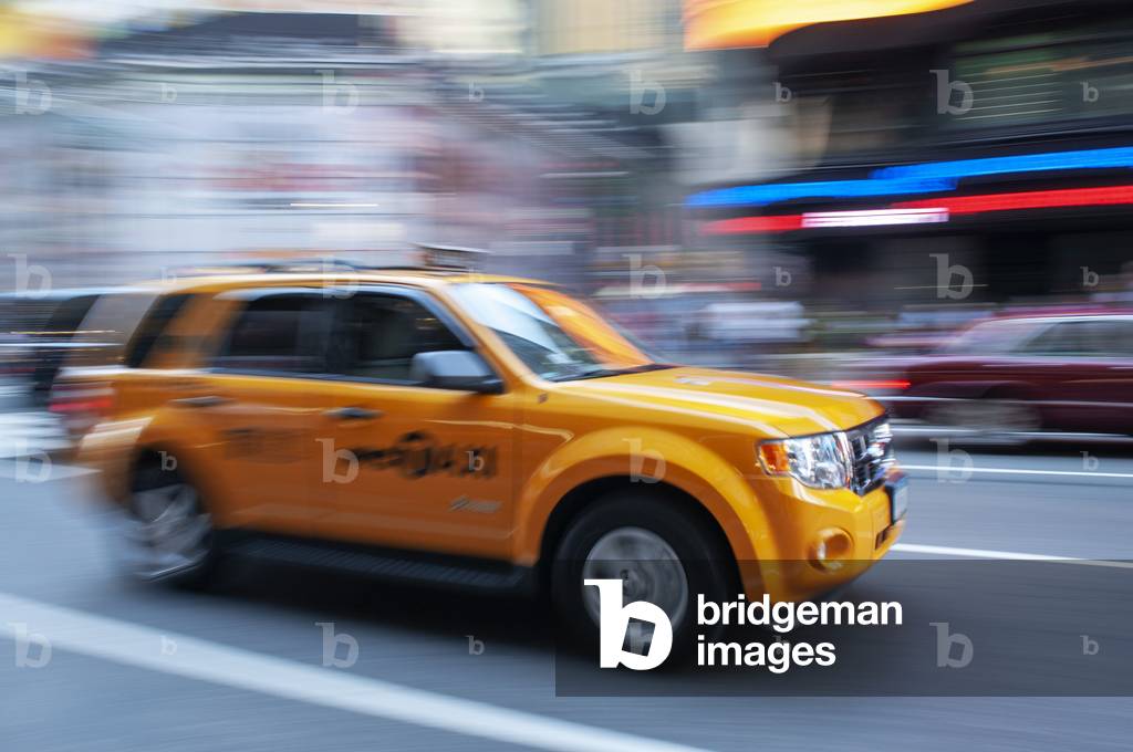 Yellow New York taxi cab driving fast on a street in New York City, USA (photo)