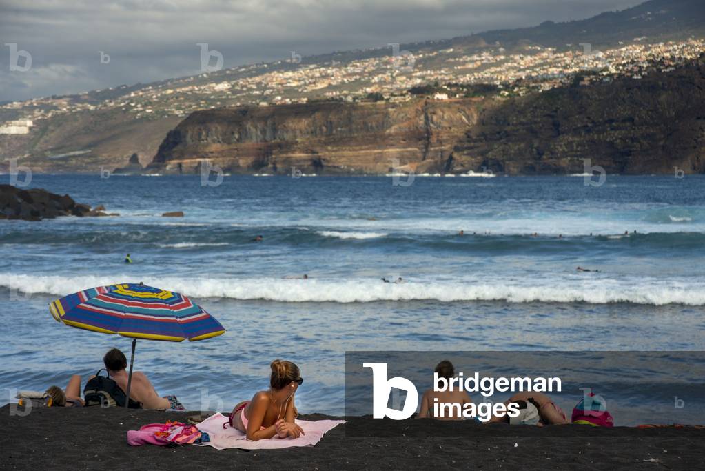Tourists at los gigantes cliffs volcanic black sand beach in Puerto de la Cruz, Tenerife Island, Canary Islands, Spain (photo)