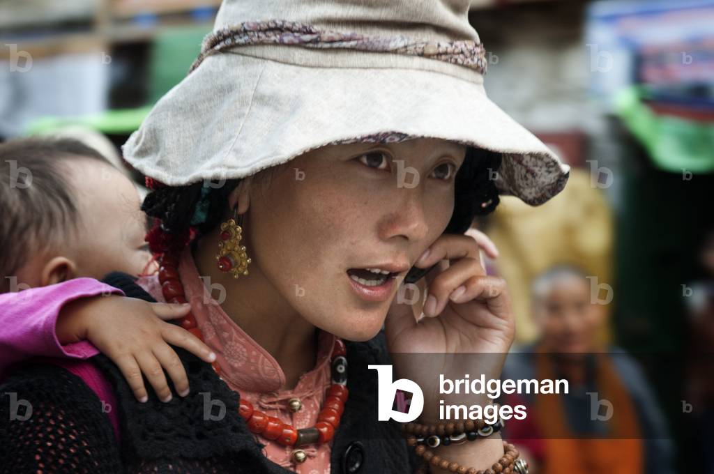 A woman carrying her son on the streets of Lhasa, Bakhor square, Lhasa, Tibet (photo)