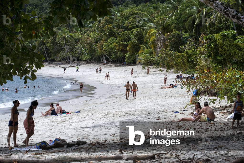 White sand Beach Manuel Antonio National Park Puntarenas Costa Rica, Tropical beach and bay with flowering tropical rainforest trees and people on beach Manuel Antonio National Park, Costa Rica (photo)