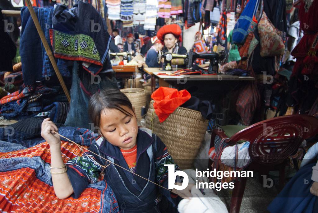 Black hmong women making and selling tribal handicrafts and clothes iniside the market in Sapa, Lao Cai Province, Vietnam (photo)