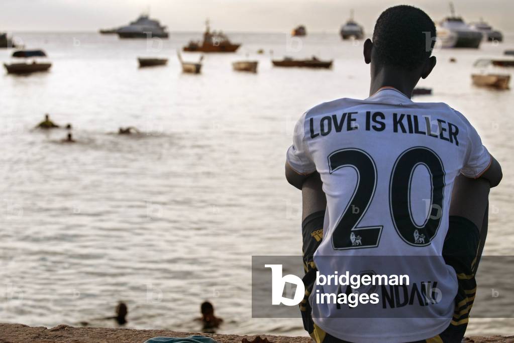 Local boy look the fishermen in the Malecon next to the pier in Stone Town, Zanzibar, Tanzania, Africa (photo)