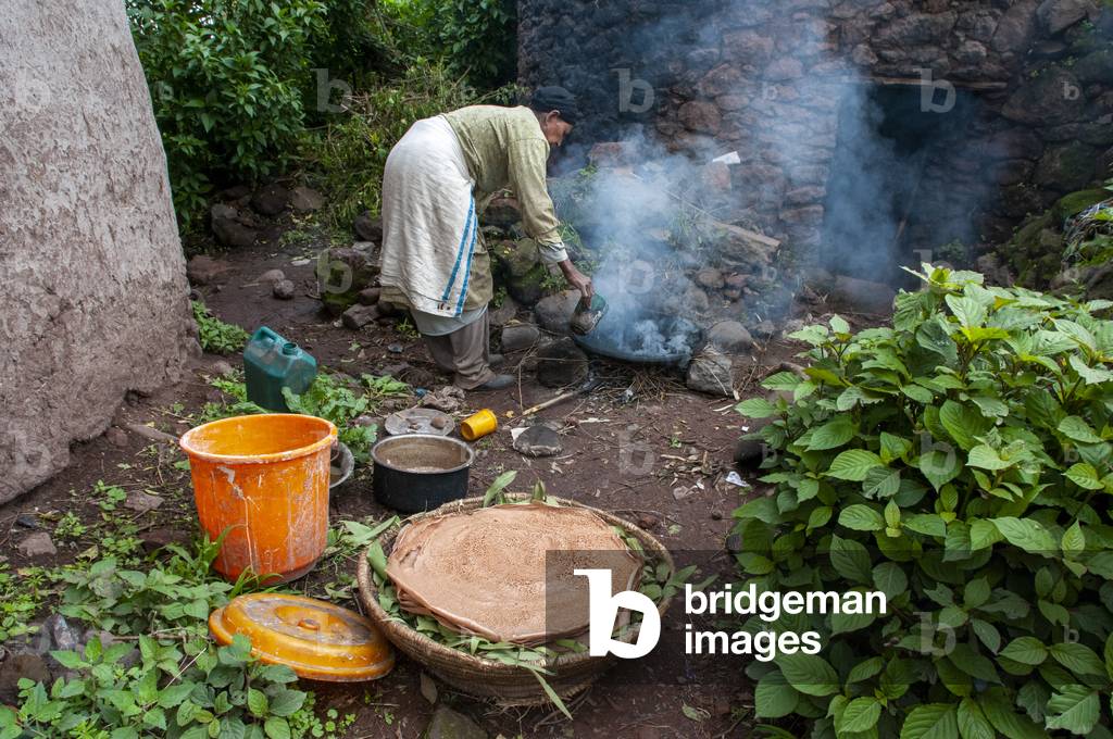 Woman cooking Injera pancake like bread on a mogogo over a fire, Lalibela, Amhara region, Ethiopia (photo)