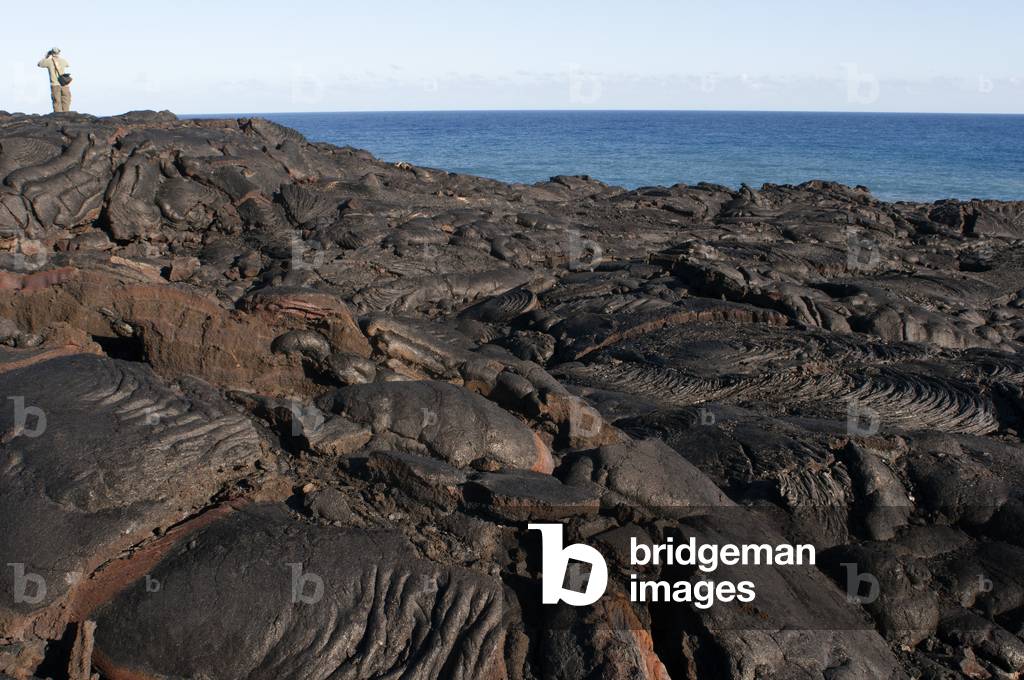 Tourists walking over the black lava mountains near Chain of Craters Road, Hawaii Volcanoes National Park, Big Island, Hawaii (photo)