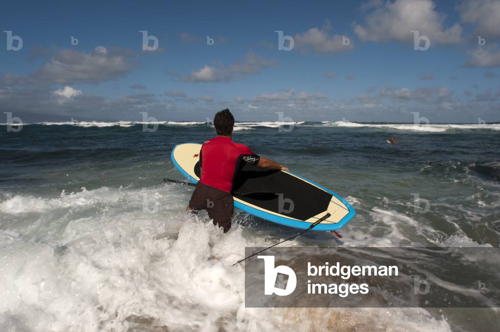 Surfer leaving the water at Hookipa Beach, Maui, Hawaii (photo)