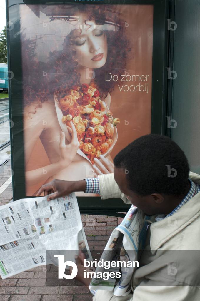 Man reading a newspaper in Brussels tram train stop in Brussels, Belgium (photo)
