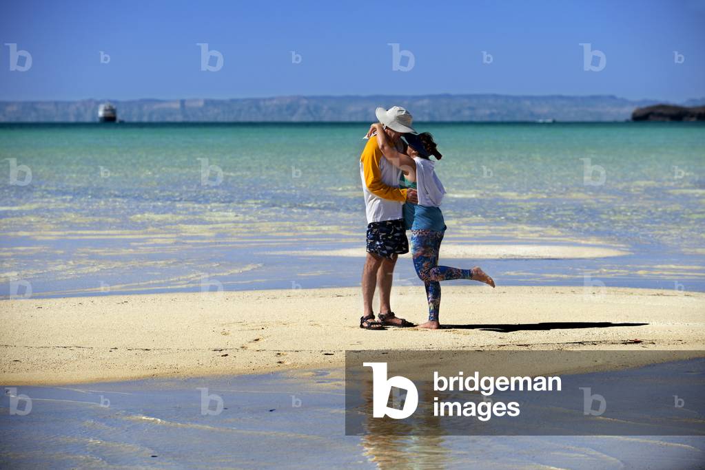 Tourists kissing in the beach of Isla Espiritu Santo island, Sea of Cortez, Baja California, Mexico (photo)