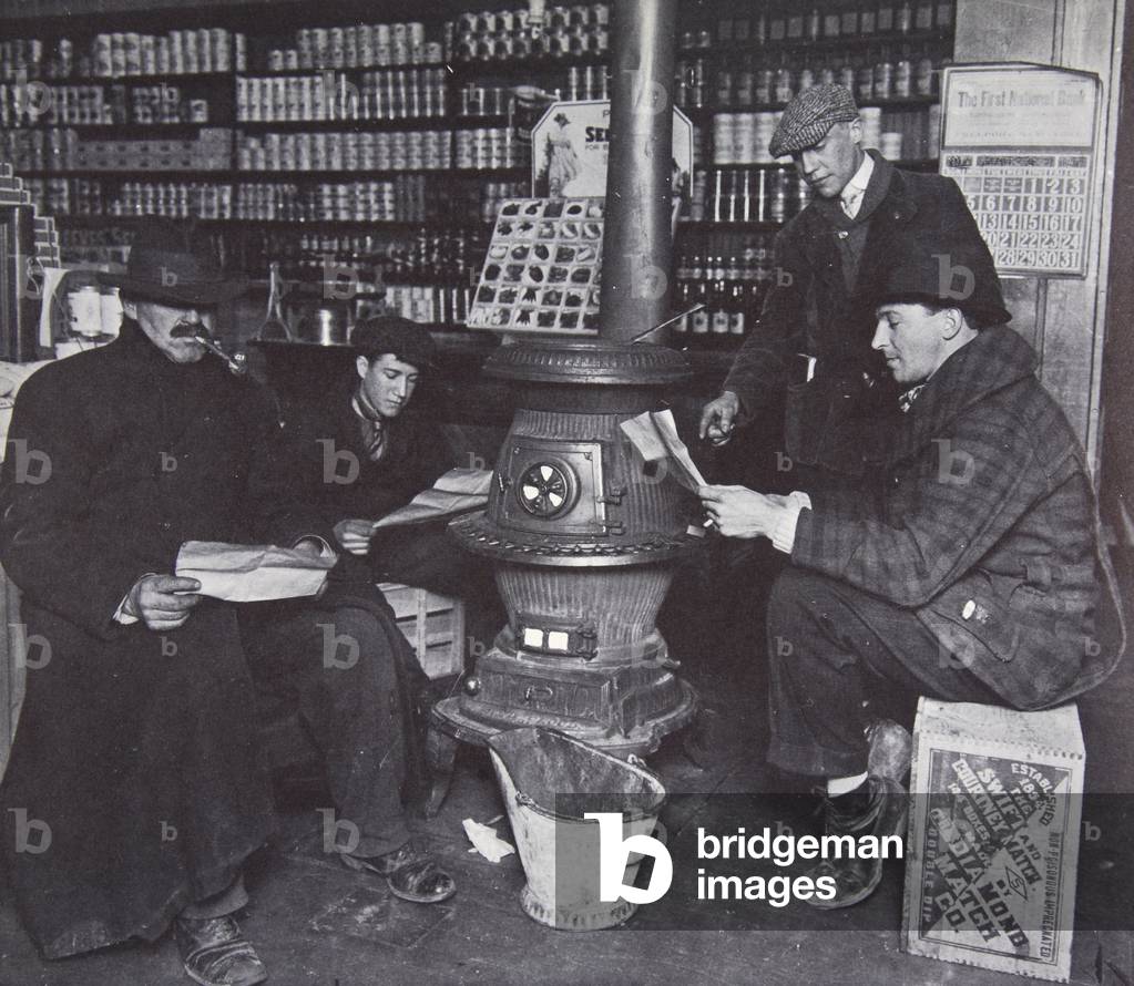 A group of men around a stove in an American store, c.1910 (sepia photo)