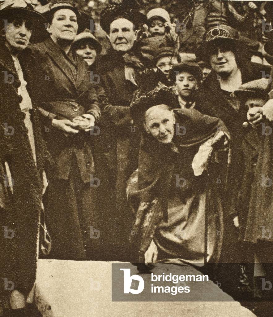 Poor widows pick up sixpences from a tombstone on Good Friday (sepia photo)