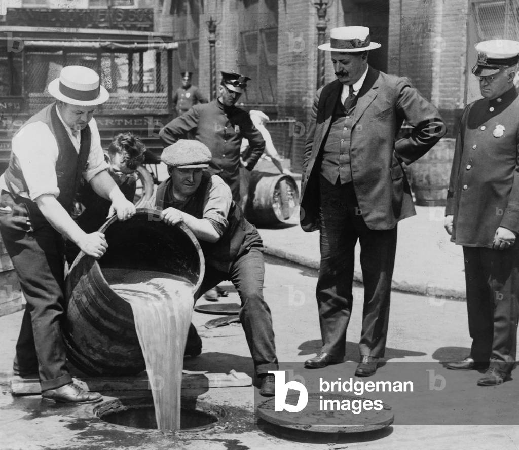 Agents pouring alcohol down a sewer during Prohibition, pub. 1921 (b/w photo)