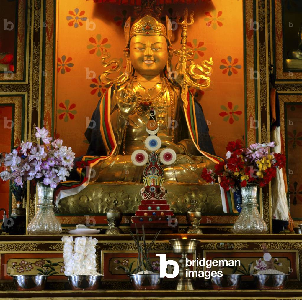 Goldene Statue eines sitzenden Buddha, umgeben von Blumen (Foto)