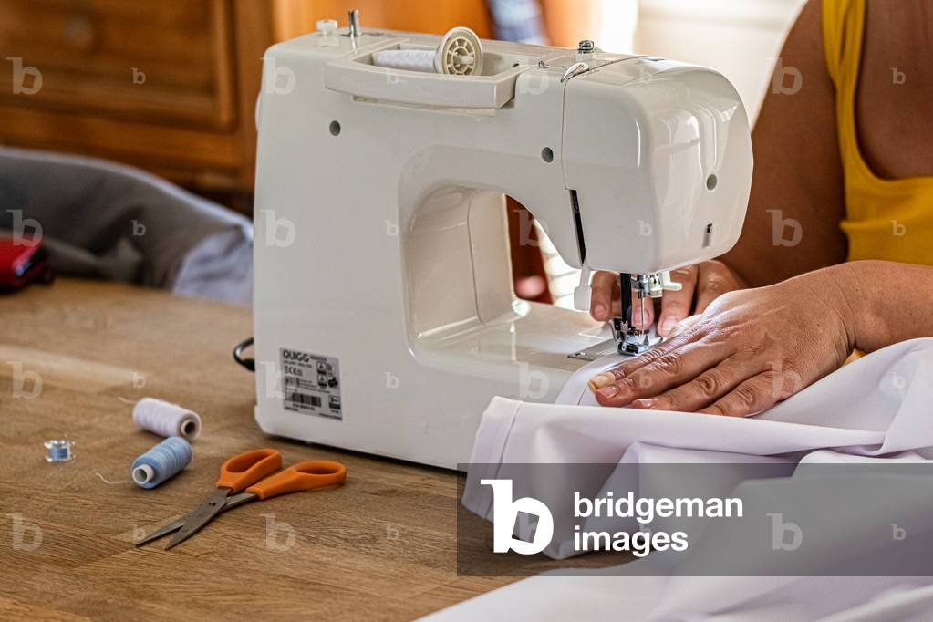 Sewing machine up close, on the foot and the needle, making smocks for caregivers, April 2020 (photo)