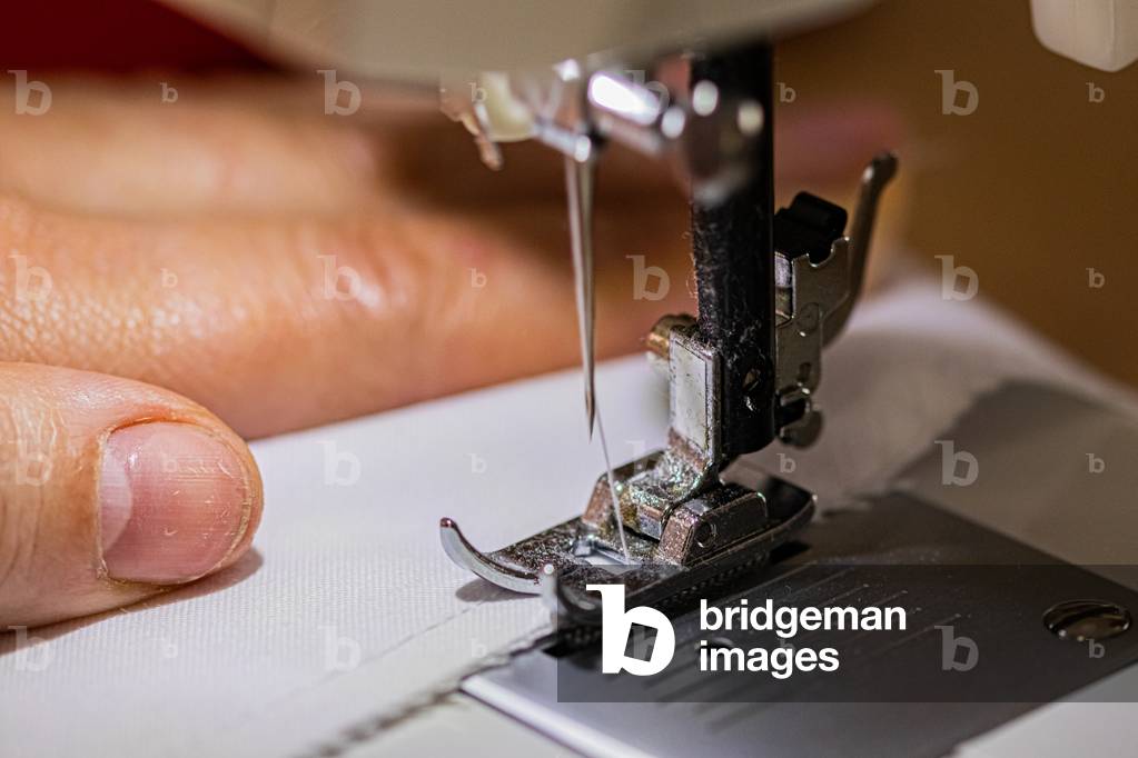 Sewing machine up close, on the foot and the needle, making smocks for caregivers, April 2020 (photo)