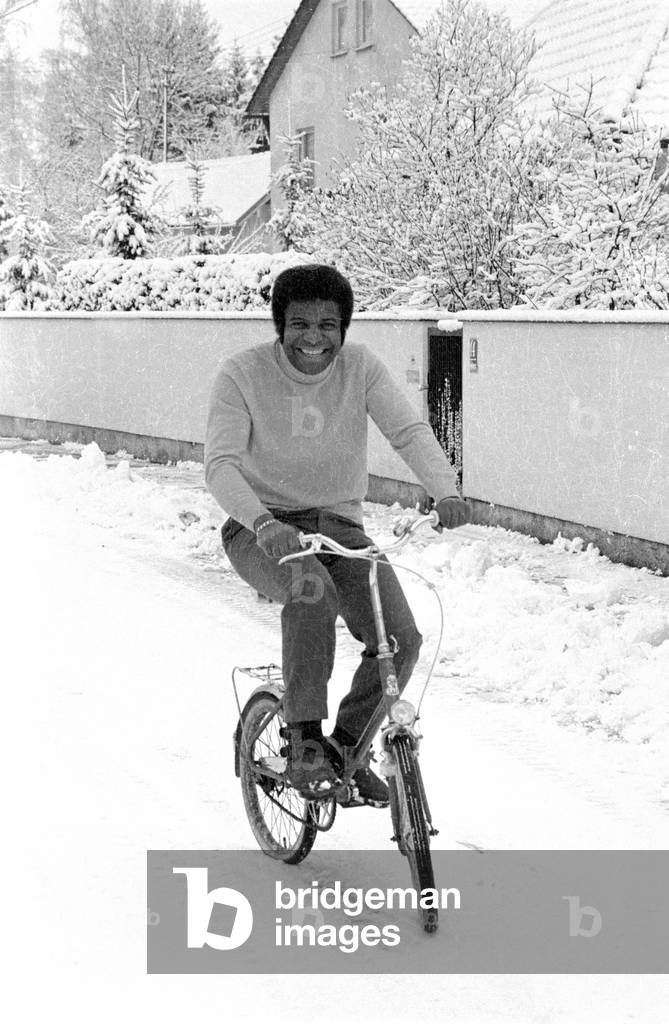Roberto Blanco with bike in the snow, 1971 (b/w photo)