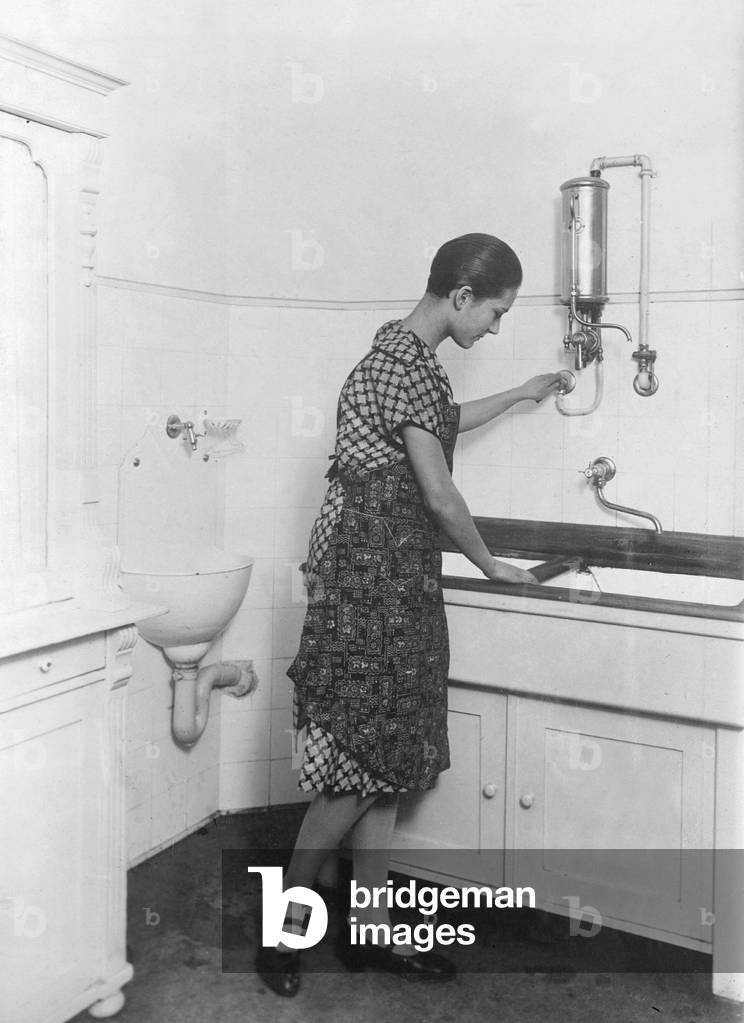Housewife at a modern sink with gas boiler, 1927 (b/w photo)
