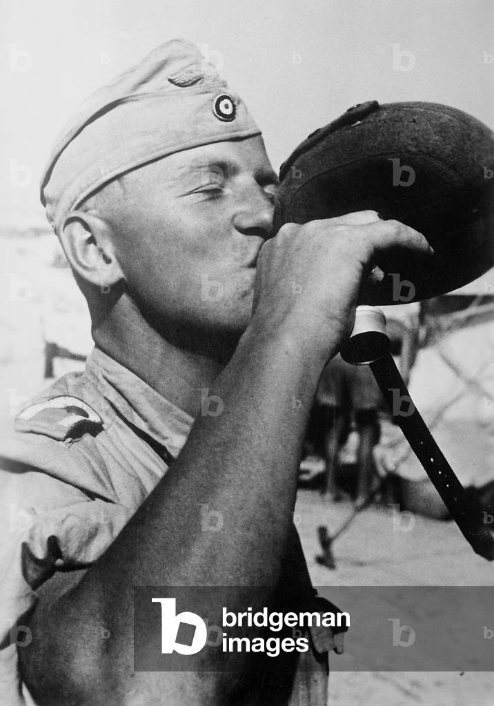 A German soldier drinking from a water bottle, 1942 (b/w photo)