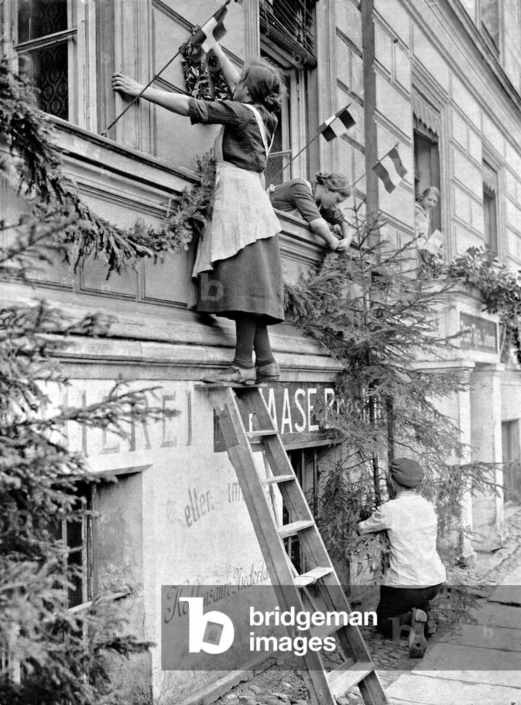 Men and women decorate their houses before the arrival of the Reichswehr troops, 1922 (b/w photo)