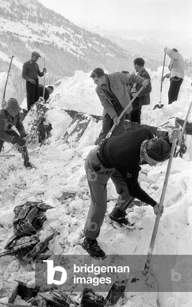 After an avalanche rescuers dig their way through the snow to a building, 1954 (b/w photo)
